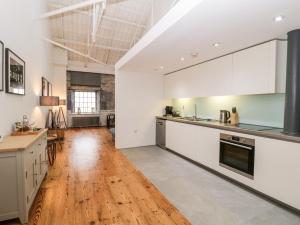 uma cozinha com armários brancos e piso em madeira em Clarence Riverside, Royal William Yard em Plymouth
