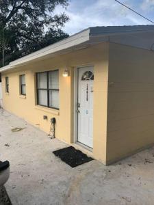 een klein geel huis met een witte deur bij Pinecrest home away from home. in Tampa