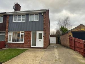 una casa de ladrillo con una puerta blanca y un garaje en Cosy 3BR Modern Home Middlesbrough, en Middlesbrough