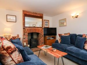 a living room with blue couches and a fireplace at Cobblers Cottage, Southwold in Southwold