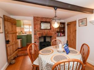 a dining room with a table and a fireplace at Cobblers Cottage, Southwold in Southwold