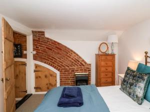 a bedroom with a bed and a brick fireplace at Cobblers Cottage, Southwold in Southwold