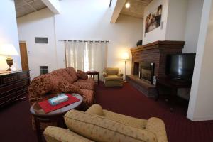 sala de estar con sofás, TV y chimenea en Fireside Inn and Suites Bangor, en Bangor