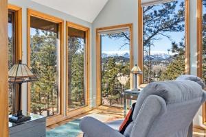 ein Wohnzimmer mit großen Fenstern und einem Stuhl in der Unterkunft Vista of Lake Estes by Estes Park Homes home in Estes Park