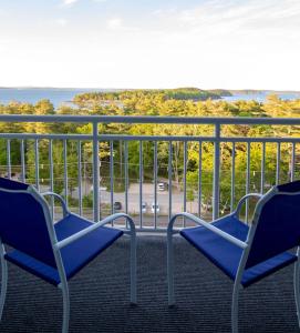 two chairs sitting on a balcony looking out at the ocean at Bluenose Inn - Bar Harbor Hotel in Bar Harbor