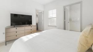ein weißes Schlafzimmer mit einem Bett und einem Flachbild-TV in der Unterkunft Landing Modern Apartment with Amazing Amenities (ID9550X82) in Forney