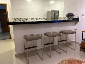 a counter with three stools in a kitchen at Apartamento Luxo em Uberaba in Uberaba