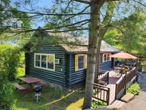 una casita azul con terraza y mesa en Cramers Point Lake Breeze, en Lake George