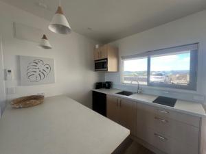 cocina con encimera blanca y ventana en Ranui Lodge, en Mangonui