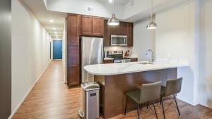 a kitchen with a sink and a counter with chairs at Landing Modern Apartment with Amazing Amenities (ID8368X66) in Omaha