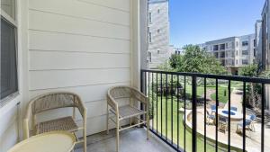 2 stoelen en tafels op een balkon met uitzicht op een park bij Landing Modern Apartment with Amazing Amenities (ID7650X68) in Dallas
