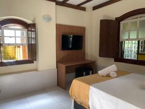 a bedroom with a bed and a tv and a window at Pousada Serra da Bocaina Paraty in Paraty