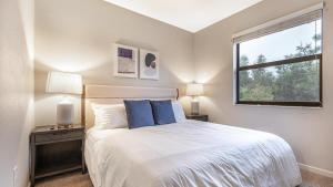 ein Schlafzimmer mit einem Bett mit blauen Kissen und einem Fenster in der Unterkunft Landing Modern Apartment with Amazing Amenities (ID8214X04) in Fort Myers