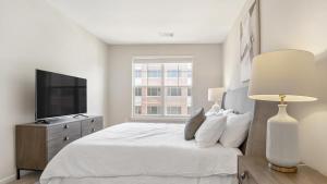 um quarto branco com uma cama e uma televisão em Landing Modern Apartment with Amazing Amenities (ID7965X79) em Leesburg