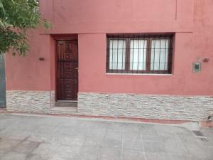 czerwony budynek z dwoma oknami i drzwiami w obiekcie dulce claudina w mieście Mercedes