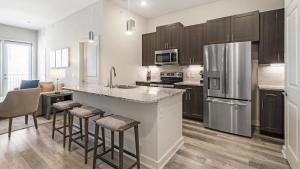 a kitchen with a refrigerator and a counter with bar stools at Landing Modern Apartment with Amazing Amenities (ID9874X53) in Dallas
