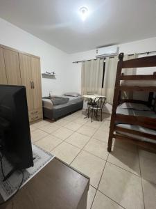 een woonkamer met een flatscreen-tv en een bank bij Kit Net Vitoria 01 in Bauru