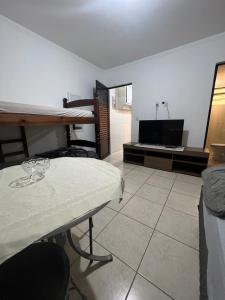 een woonkamer met een tafel en een televisie bij Kit Net Vitoria 01 in Bauru