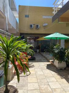 un patio avec des plantes et un parasol en face d'un bâtiment dans l'établissement Pousada Residência dos Sonhos, à Porto de Galinhas