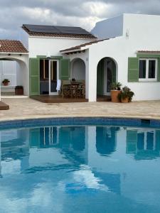 uma villa com piscina em frente a uma casa em Apartamento nº 1 Cala Blanca em Cala Blanca