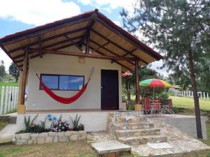 a small house with awning and a table and umbrella at Linda mini casa campestre con Jacuzzi, chimenea... in Paipa