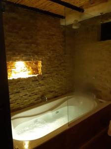 a bath tub in a room with a brick wall at Linda mini casa campestre con Jacuzzi, chimenea... in Paipa