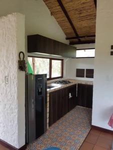 cocina con nevera negra en una habitación en Linda mini casa campestre con Jacuzzi, chimenea... en Paipa
