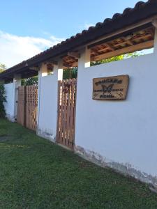 a white wall with a wooden gate and a sign on it at POUSADA BORBOLETA AZUL in Ilha Comprida