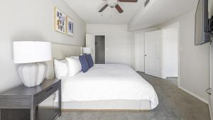 ein Schlafzimmer mit einem weißen Bett und einem Tisch mit einer Lampe in der Unterkunft Landing Modern Apartment with Amazing Amenities (ID7793X62) in Greenwood Village