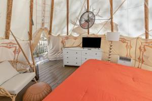 um quarto com uma cama e um relógio numa tenda em Furnished Teepee/Glamping/Kayak Ramp/King Bed em Stanton