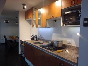 a kitchen with a stove and a sink and a microwave at Duplex LOFT. céntrico a unas cuadras de Recoleta in Cajamarca