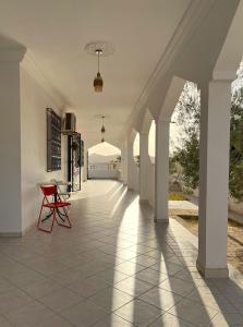 un couloir vide d'une maison avec une chaise rouge dans l'établissement Maison d'hôtes DAR DRISS, à Matmata