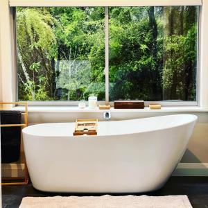 a large white bath tub in front of a window at Wairimu View Lodge in Waipu