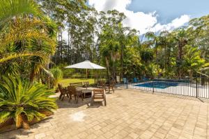 a patio with a table and chairs and an umbrella at The Palm Farm in Smiths Lake