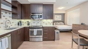 una cocina con armarios de madera y una cama en una habitación en Landing Modern Apartment with Amazing Amenities (ID6801) en West Sacramento