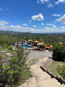 un complexe avec une piscine au milieu d'un champ dans l'établissement Cabañas Terrazas del Sol, à Villa Carlos Paz