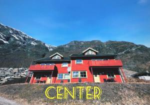 a red building on a hill with mountains in the background at Brekke Apartments in Flåm