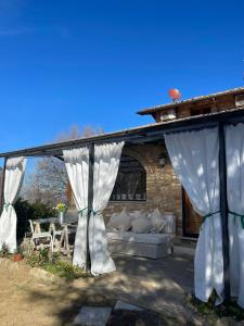 a pavilion with white curtains and a couch at mikipongTWO in Montepulciano