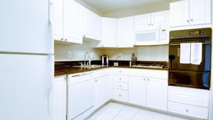 a white kitchen with white cabinets and black appliances at Landing Modern Apartment with Amazing Amenities (ID2805X39) 