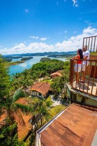 two people standing on a balcony looking out over a river at Pousada Iguatiba in Paraibuna