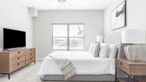 een witte slaapkamer met een bed en een televisie bij Landing Modern Apartment with Amazing Amenities (ID1206X872) in San Marcos
