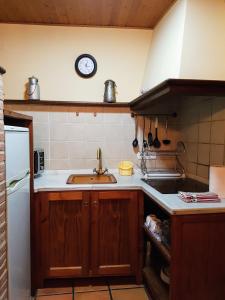 uma cozinha com um lavatório e um relógio na parede em Casa Rural TioMoreno by Naturadrada em La Adrada