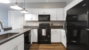 een keuken met een zwarte koelkast en witte kasten bij Landing Modern Apartment with Amazing Amenities (ID8145X4) in Toledo