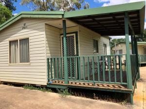 una casa con portico con ringhiera verde di Crossroad Cabins Tooraweenah 