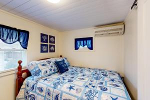 a bedroom with a blue and white bed and a window at The Gull's Nest at Isle of Wight in Ocean City