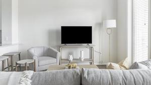 a white living room with a couch and a tv at Landing Modern Apartment with Amazing Amenities (ID1058X75) in San Antonio