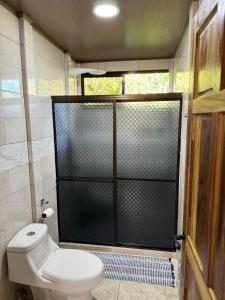 baño con aseo y puerta de ducha de cristal en Hospedaje Kukul San Vito, en San Vito