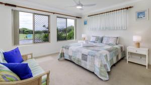 a bedroom with a bed and a couch and windows at Walk to Surf Beach - Ground floor apartment - Bribie Horizons Boyd St, Woorim in Woorim