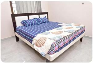 uma cama com um edredão e almofadas azuis e brancas em NRI NC Homestays em Tirupati