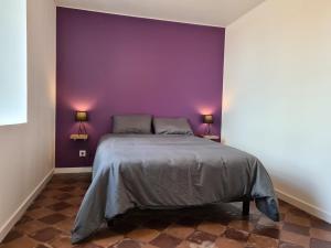 ein Schlafzimmer mit einem Bett mit einer lila Wand in der Unterkunft Gîte Crevant, 4 pièces, 8 personnes - FR-1-591-310 in Crevant